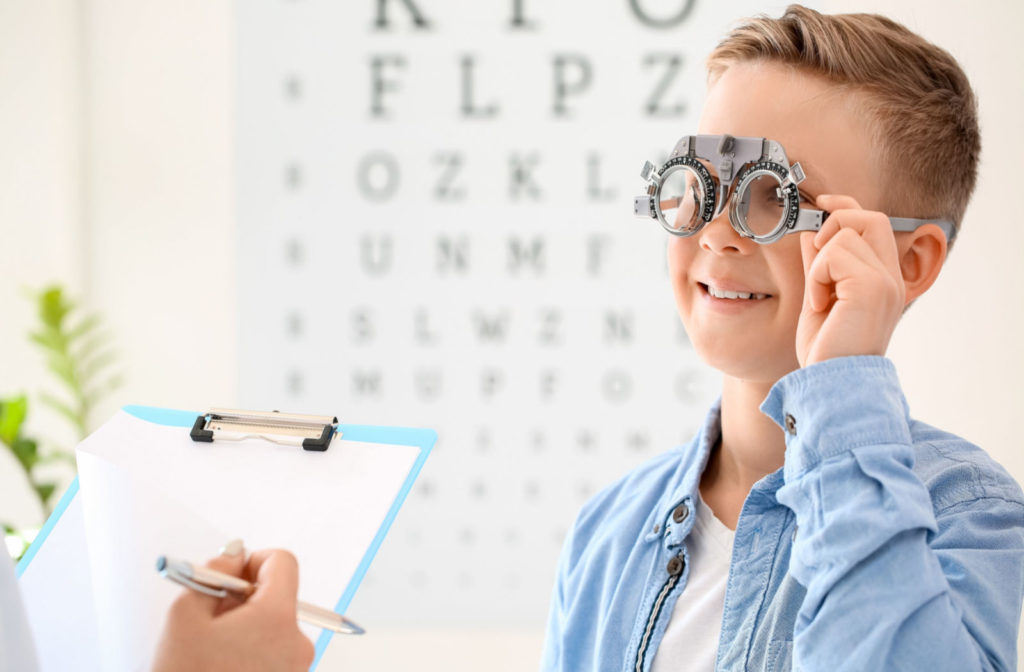 A young boy wearing trial frames is examined by an optometrist.